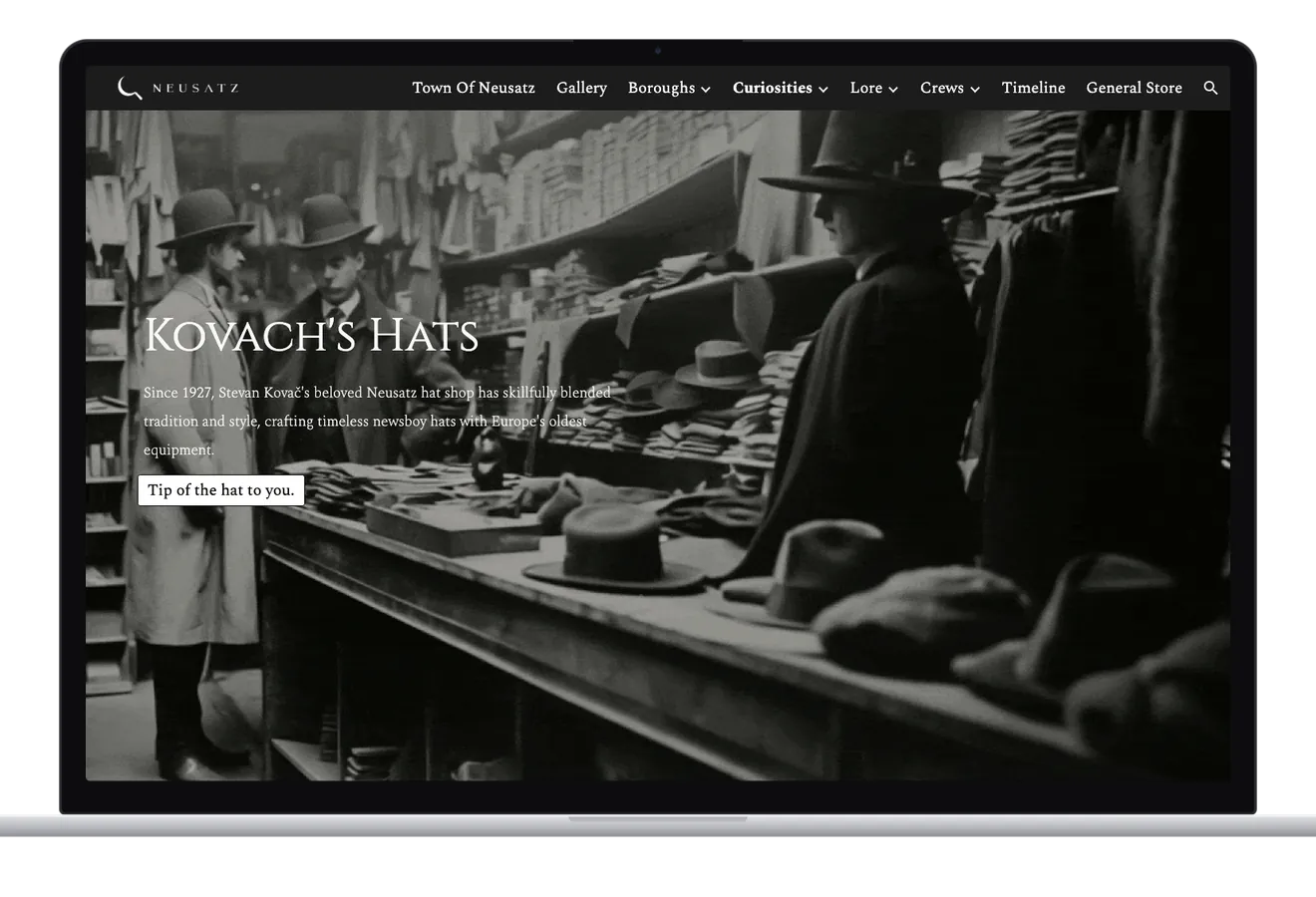 The Curiosities page on a laptop at Kovach's Hats: a black and white scene of men in hats and coats at a shop counter piled with caps, with the shop's summary and a button reading Tip of the hat to you