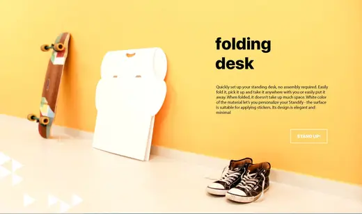 Folded Standify desk leaning on a yellow wall beside a skateboard