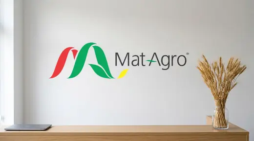 MatAgro: the horizontal Mat Agro logo in green, red, yellow and grey, painted large on the white wall above the oak reception desk of the company office, a glass vase of dried wheat ears at the end of the desk