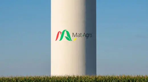 MatAgro: the horizontal Mat Agro logo painted large around a smooth white concrete grain silo standing over a corn field on the Vojvodina plain, in late afternoon sun