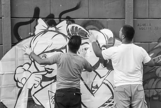 two males pasting large paper stencil not the wall