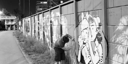 black and white photo of a man painting a mural on the wall