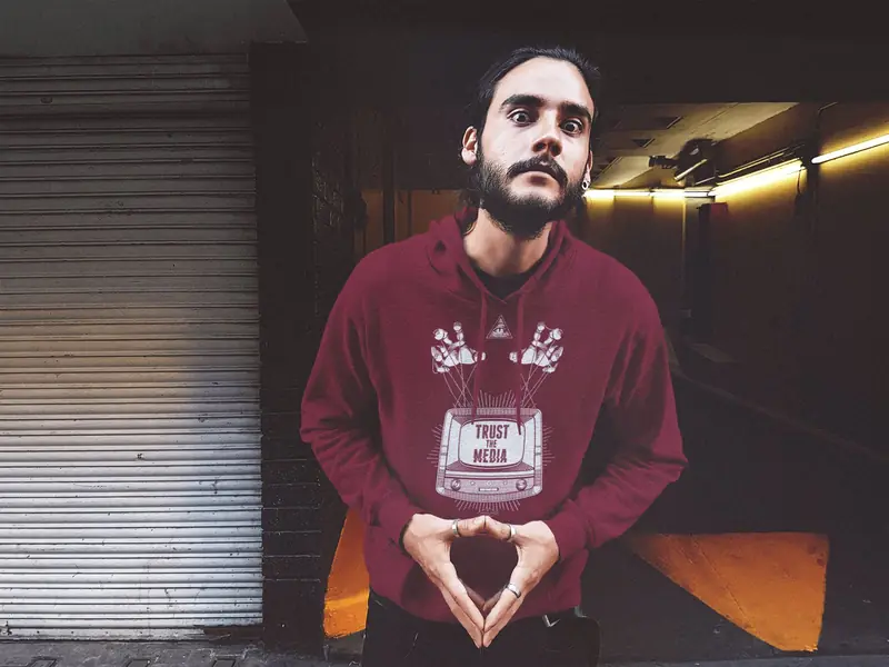 man wearing a crimson t-shirt with the trust the media graphic on it