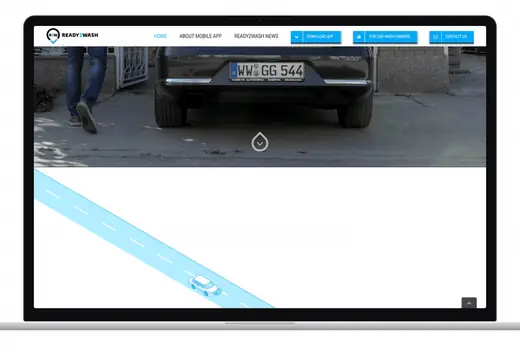The Ready2Wash website scrolling in a laptop frame: a car drives along a road past phones showing the app's features and the car-wash stations.