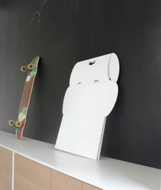 Standify: Folded desk leaning on a dark wall with a longboard