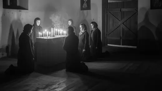 Women in headscarves lighting candles in a dark church