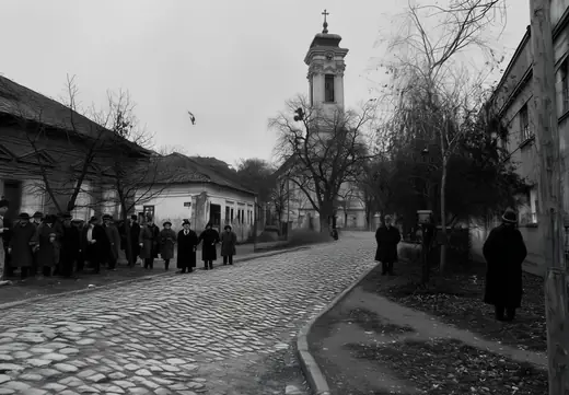 People queueing along a cobbled street toward the church tower