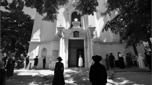 A crowd gathered in sunlight before the church front